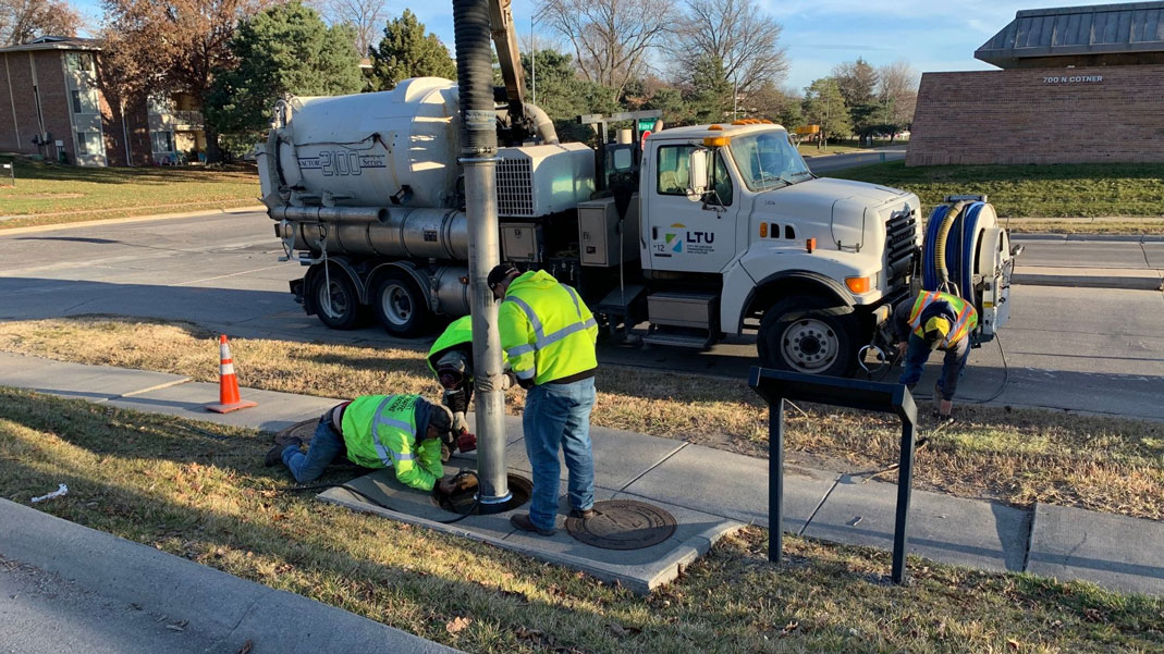 Lincoln Transportation and Utilities Operations and Maintenance team members work together to clean out a hydrodynamic separator using a vacuum truck.