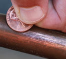 Copper pipe scratched with a penny