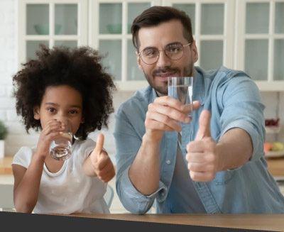 Image of a man and child giving thumbs up while each drinking a glass of water