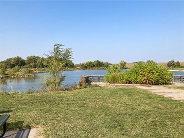 Bowling lake has many fishing spots located on its shores. This pier is located off the paved path and near a picnic table. The pier has a large native flower bed with sumac and other perennials.