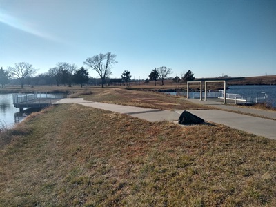A concrete path connects the accessible parking spot to the two accessible fishing piers. The pier on the left is uncovered, the pier on the right is covered to provide shade.