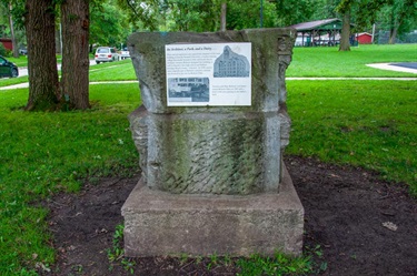 A plaque describing the park's history is placed on an concrete architectural antique from its past.