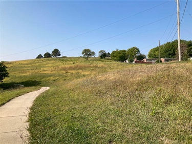 A paved walking path curves through gentle grassy hills at Arnold Heights.