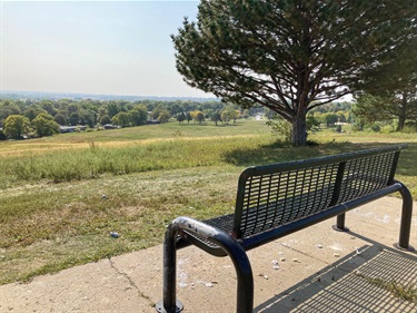 A park bench on a paved surface overlooks the hill and City of Lincoln below.