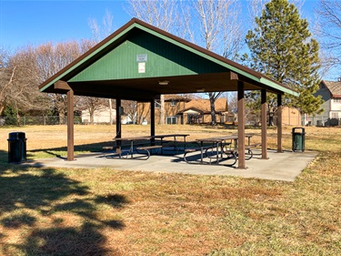This open shelter has picnic tables and is located on a concrete slab in Highlands park.