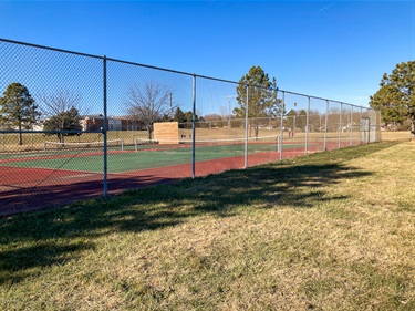 Highlands park tennis courts are surrounded by a chain link fence and located near established shade trees.