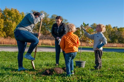 Two children help their parents plant a tree in Mahoney Park.