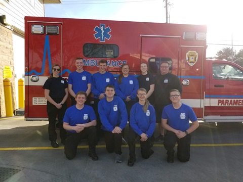 The group of fire explorers posing in front of an ambulance