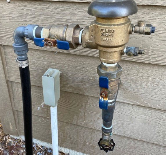 Residential irrigation backflow preventer assembly mounted on exterior piping
