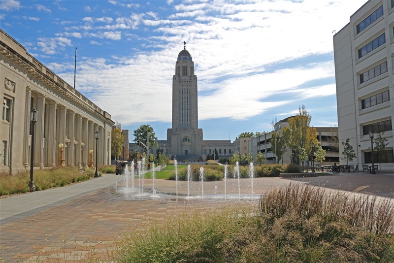 Streams of water shoot up from the bricks paving the ground the Capitol building in the background and native plants in the foreground