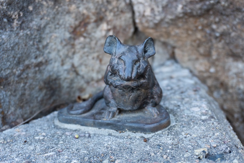close up of a bronze replica of a mouse surrounded by stone