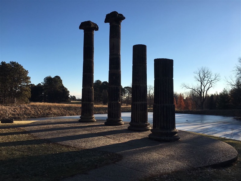 The four sandstone columns at Pioneers Park casting shadows in front of a landscape