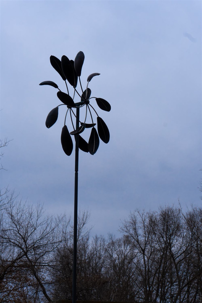 A double-sided wind sculpture made up of feather like pieces that spin.