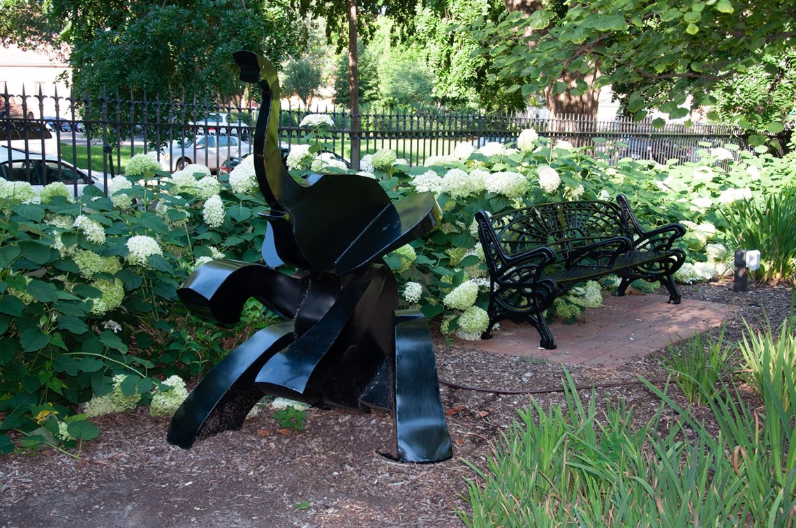 A metal elephant amid flowers and grass