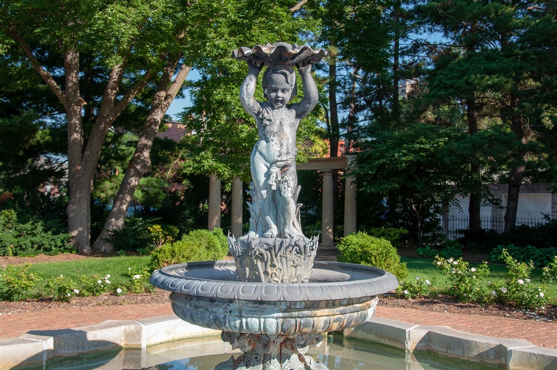 A cherub on a pedestal in the middle of the fountain