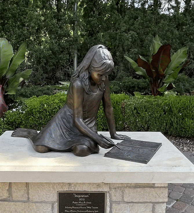 rotating around a bronze sculpture of a young girl sitting on a stone slab drawing in a notebook. 