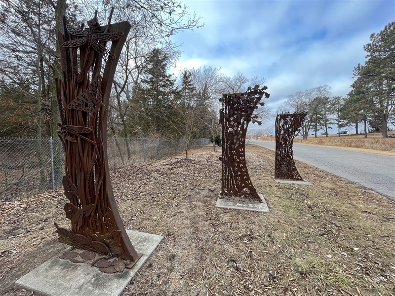 Three welded entry panels featuring various plants and animals.