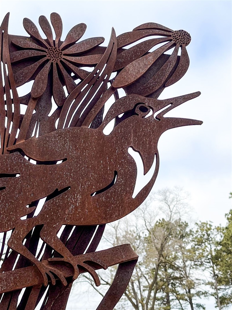 On the corner of one of the entry panels is a small bird with some flowers in the background, both made of metal. 