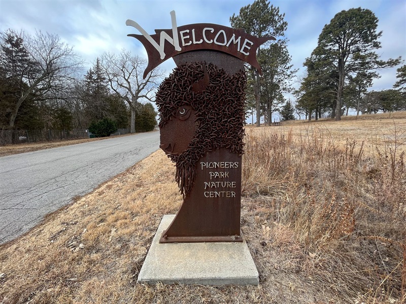 A welcome sign featuring the metal head of a bison and the words 