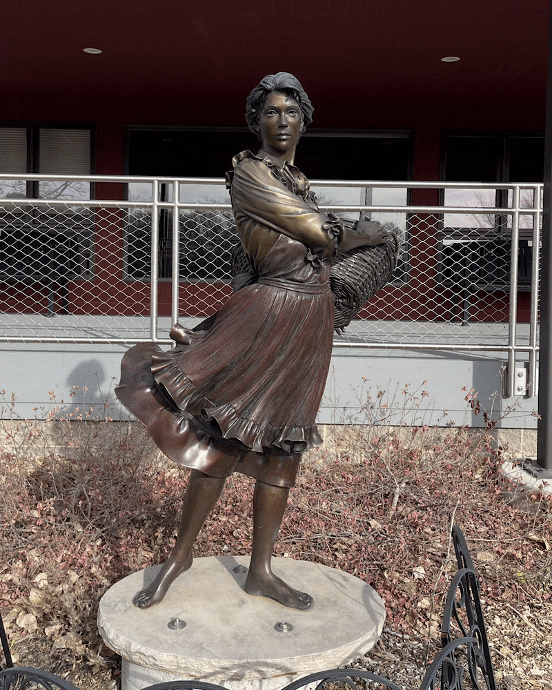 Rotating around the sculpture Prairie Flowers to show the bronze young woman holding a basket of flowers from all sides 