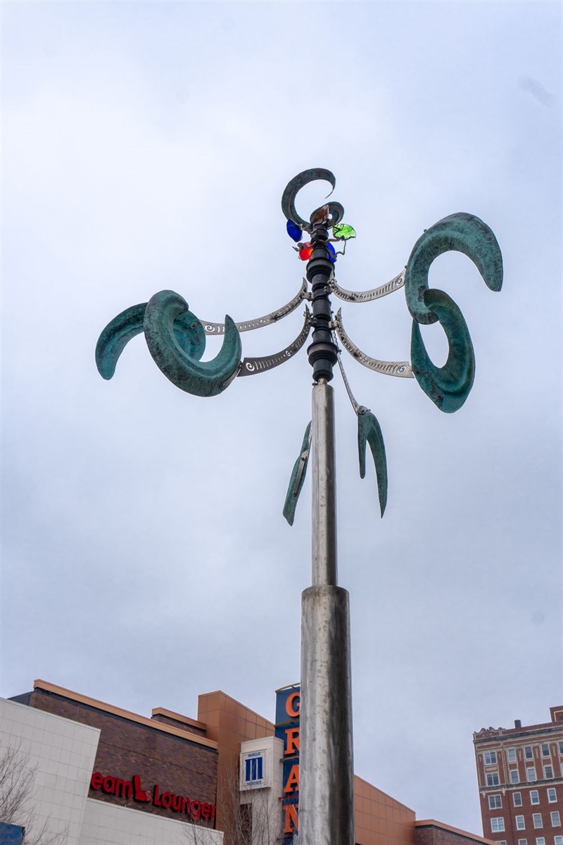 A sculpture that moves in the wind featuring arms that end in c shapes and jewels at the top.