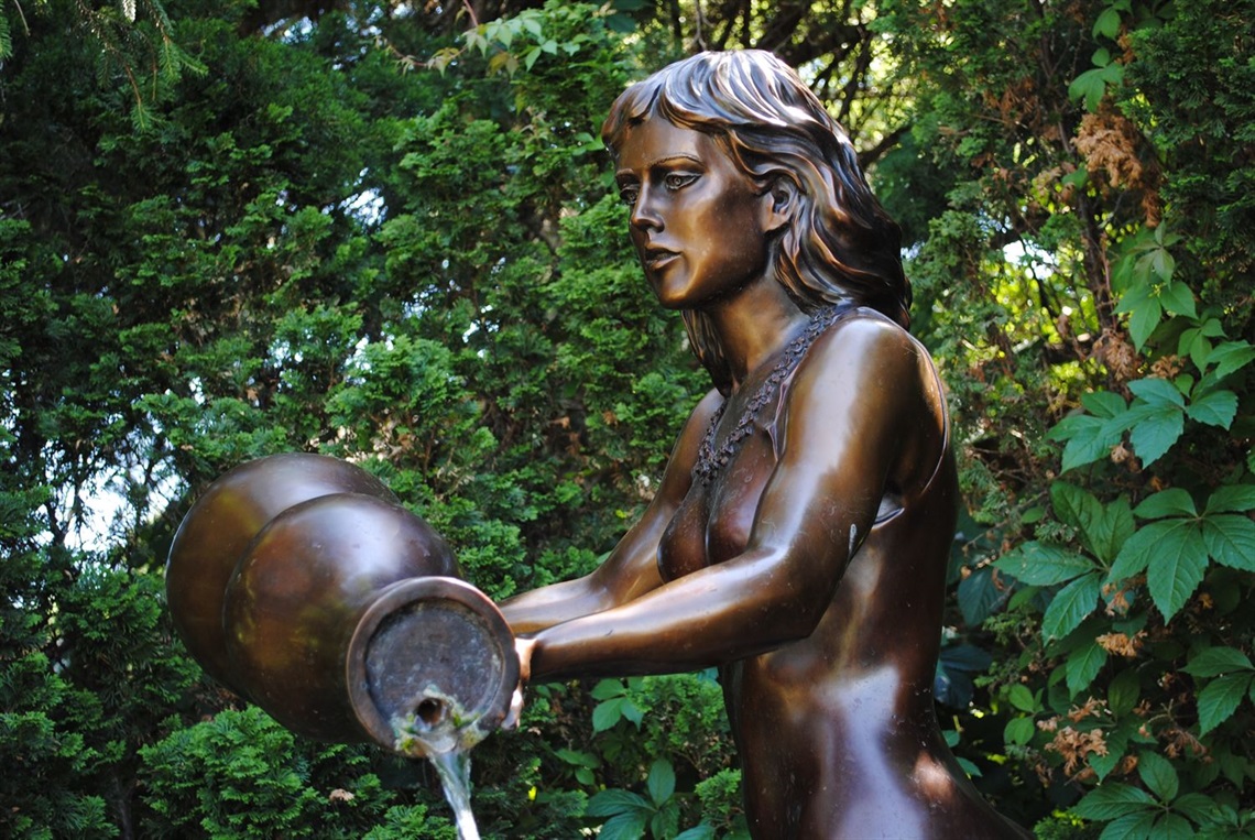 Close up of a the bronze sculpture, Rebekah at the Well, featuring a young woman pouring water out of a jug