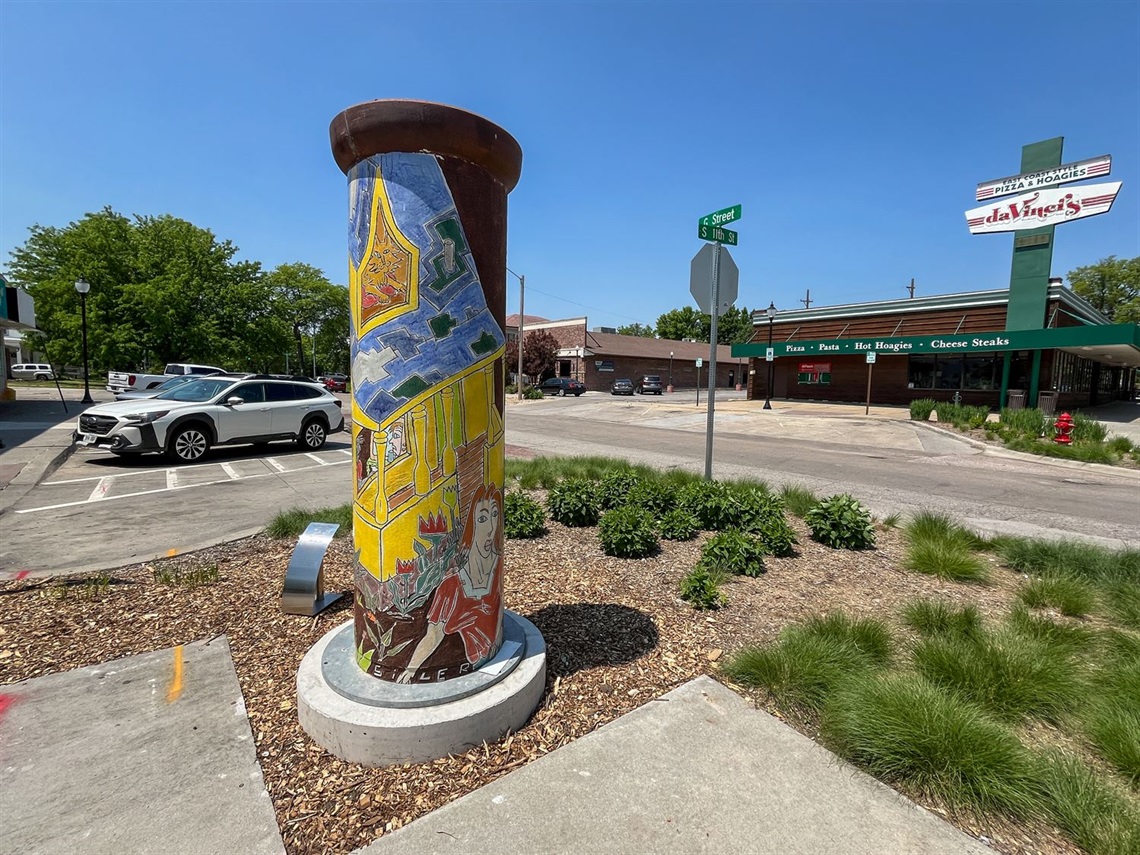 The cylindrical sculpture, The Blue Roofed House, sitting on a street corner.