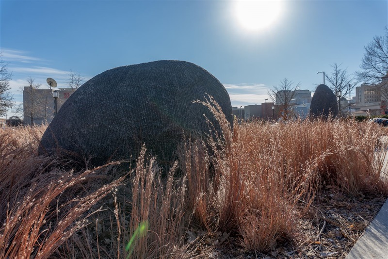 two textured stones emerging from the prairie grasses that surround them, one closer and the other rising in the foreground. 
