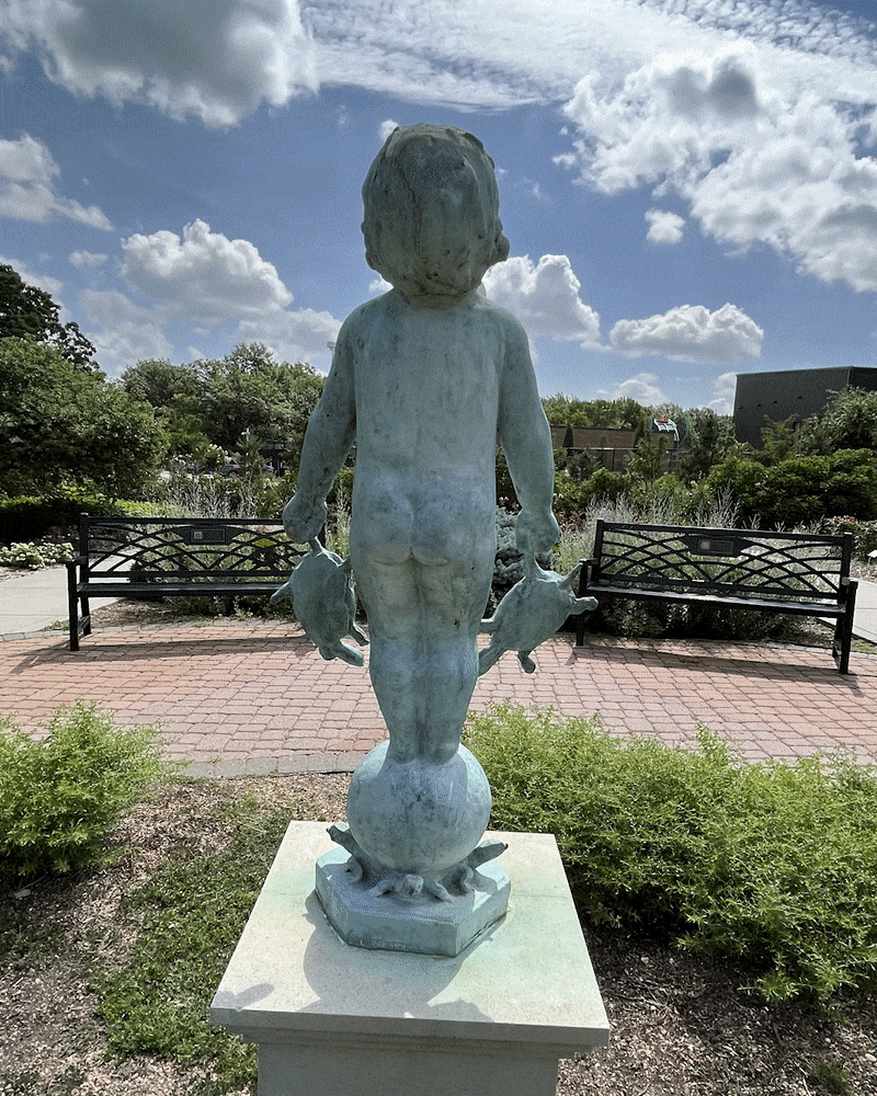 Rotating around a sculpture of a small child holding two turtles in either hand, smiling up at the shining sun. 
