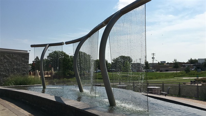 Three poles rise from a pool of water each with waterfall coming out of the top cross beam. 