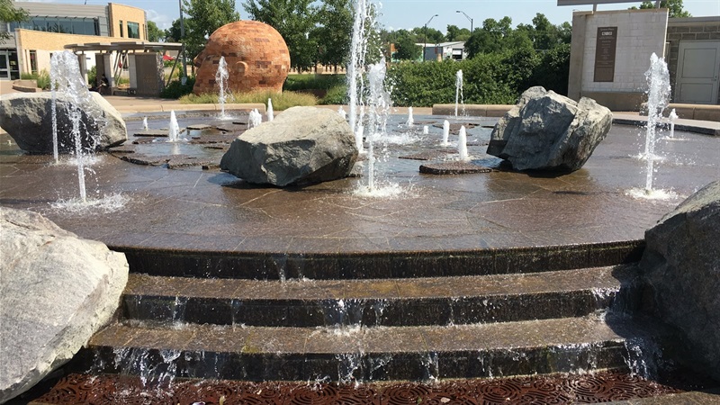 A fountain with a collection of upward streams of water and rocks on top of the elevated surface.