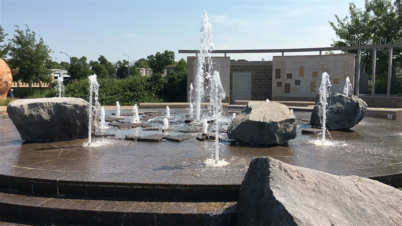 Streams of water shoot upward from a stair-raised platform with rocks scattered through the streams.