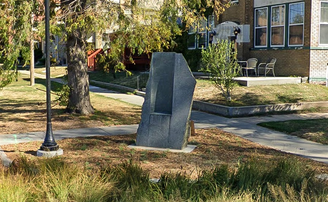 A slab of carved granite rising from the grass from a small distance
