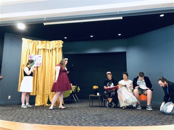 A group of 6 campers are in costume, delivering their lines on stage.