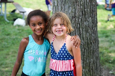 Two young campers smile together at a picnic.