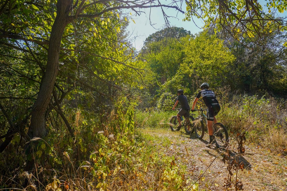 Two bikers take off down a mountain bike path 