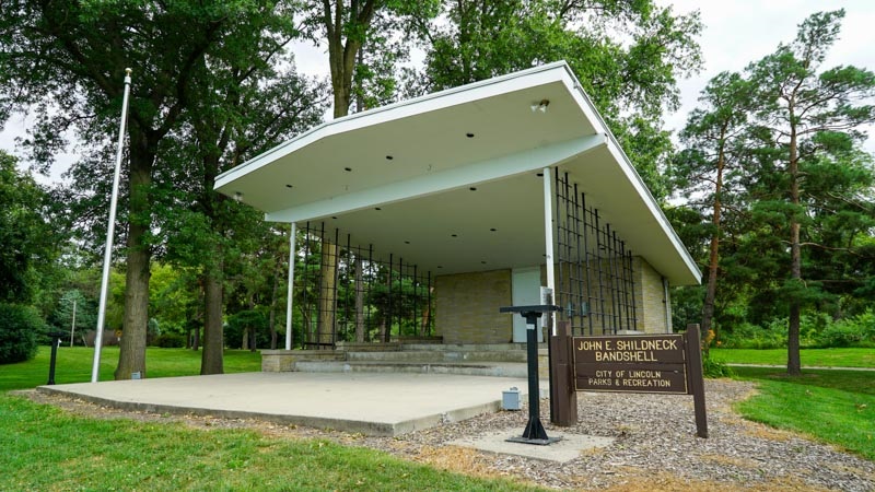  A Brown Park’s sign reads “John E. Shildneck Bandshell City of Lincoln Parks & Recreation” In front of the bandshell’s unique checked metal sides.