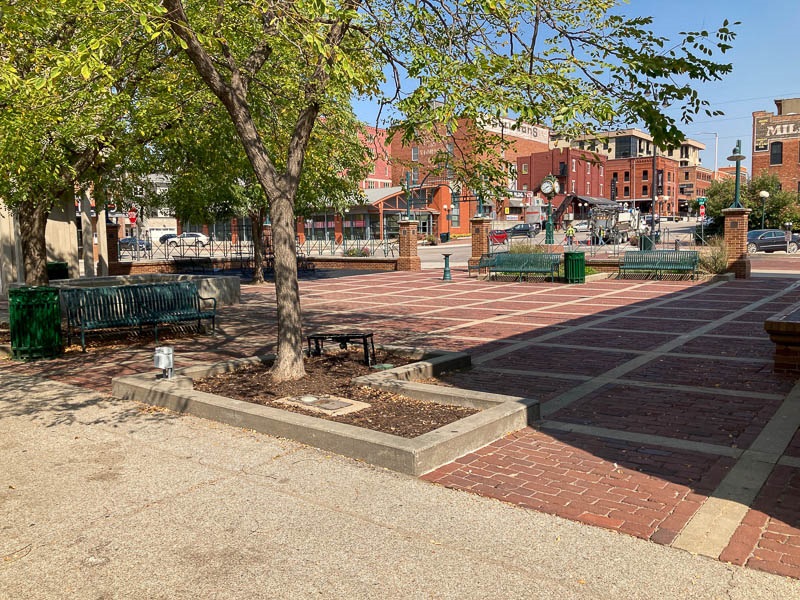 A brick paved plaza featuring shade trees and benches in the Historic Haymarket setting.
