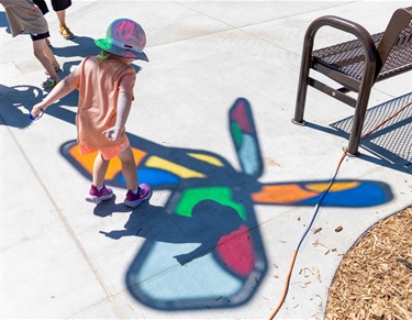 Child dances ontop of a colored shadow