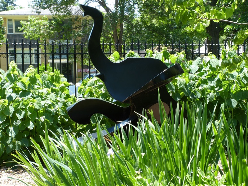 A small metal elephant emerging from the flowers and grasses