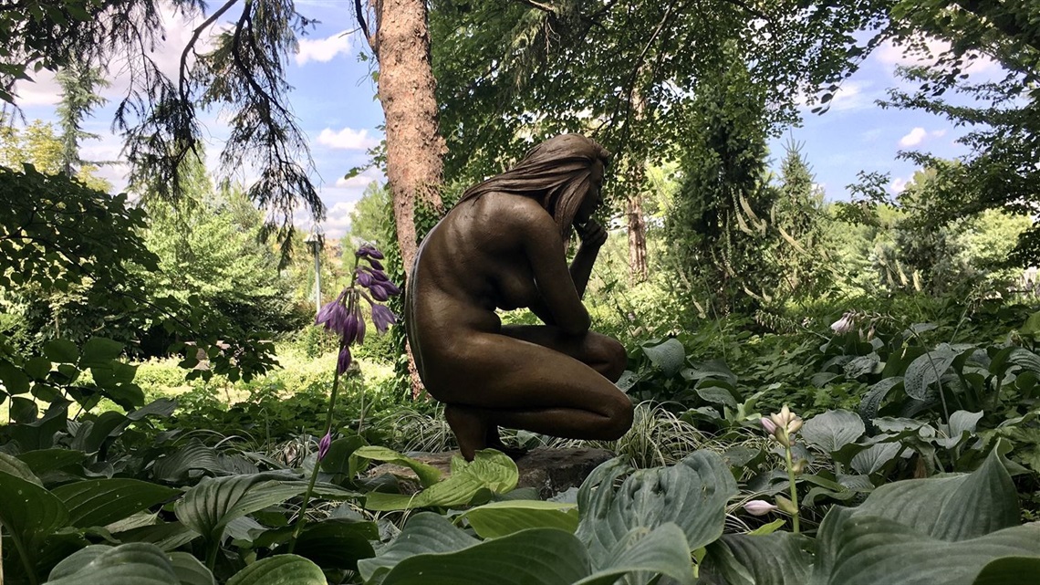 Kneeling Figure surrounded by greenery and trees