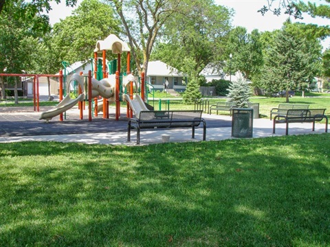 The playground at the American Legion Park has slides, swings, and a rubber play surface. There are large shade trees and benches lining the area provide space to rest and enjoy the space.