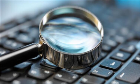 Maginifying glass resting on a computer keyboard