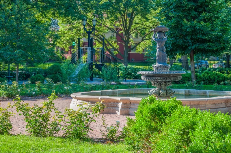 This French, baroque, cast iron fountain with its cherubim holding a shell, was created in the 1840's and is an original park feature. It's the center of the brick strolling path, bordered by white roses and boxwoods. The parks playground is nearby.
